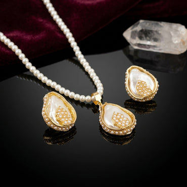 Gold-Tone Baroque Shell Pearl & Seed Pearl Cluster Teardrop Pendant Necklace & Earrings Set on black mirror surface with white crystal quartz and deep burgundy velvet backdrop