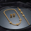 Gold Black Enamel Medusa Head Cuban Chain Necklace Bracelet Earrings Set — 3-piece matching set of heavy 22K gold-tone Cuban curb chain necklace with 5 black enamel Medusa head disc charms, matching bracelet with 5 Medusa disc charms, and black enamel Medusa disc stud earrings, luxury flat-lay on round mirror tray with dark charcoal silk backdrop
