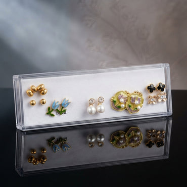 Gold Blue Tulip Black Clover Floral Enamel Pearl 5-Pair Stud Earring Set flat lay on dark black mirror surface with grey backdrop showing gold textured ball double studs blue tulip enamel studs with green leaf white CZ daisy pearl drop studs large yellow-green enamel oval floral stud with purple flower and pearl drops and black clover CZ snowflake cluster with mirror reflections below