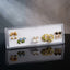 Gold Blue Tulip Black Clover Floral Enamel Pearl 5-Pair Stud Earring Set flat lay on dark black mirror surface with grey backdrop showing gold textured ball double studs blue tulip enamel studs with green leaf white CZ daisy pearl drop studs large yellow-green enamel oval floral stud with purple flower and pearl drops and black clover CZ snowflake cluster with mirror reflections below