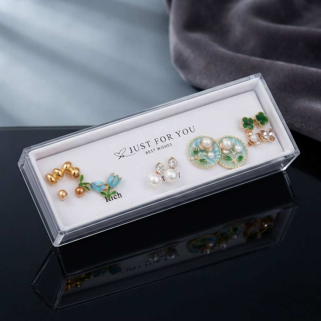 Gold Blue Tulip Mint Floral Pearl Green Clover 4-Pair Stud Earring Set displayed in open clear Just For You acrylic display gift box on black mirror surface with grey velvet backdrop showing all five pairs on white velvet insert with mirror reflection below