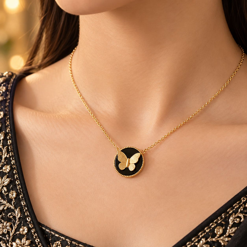 Gold Butterfly Black Onyx Disc Pendant Necklace close-up worn by model in black gold-embroidered formal outfit with gold bokeh backdrop