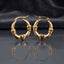 Gold Claddagh Heart and Hands Hoop Earrings pair standing side by side on dark mirror surface with charcoal slate satin backdrop showing 22K gold-tone mirror-polish hoops with smooth puffy 3D heart at base held by two detailed sculpted hands with engraved finger detail on both sides in classic Claddagh arrangement with sharp mirror reflection below