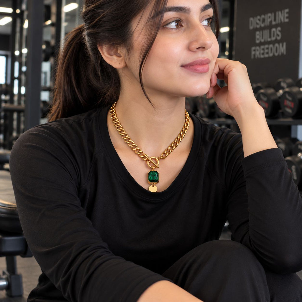 Gold Cuban Chain Emerald CZ Square Pendant Toggle Necklace worn by model in black outfit at gym setting