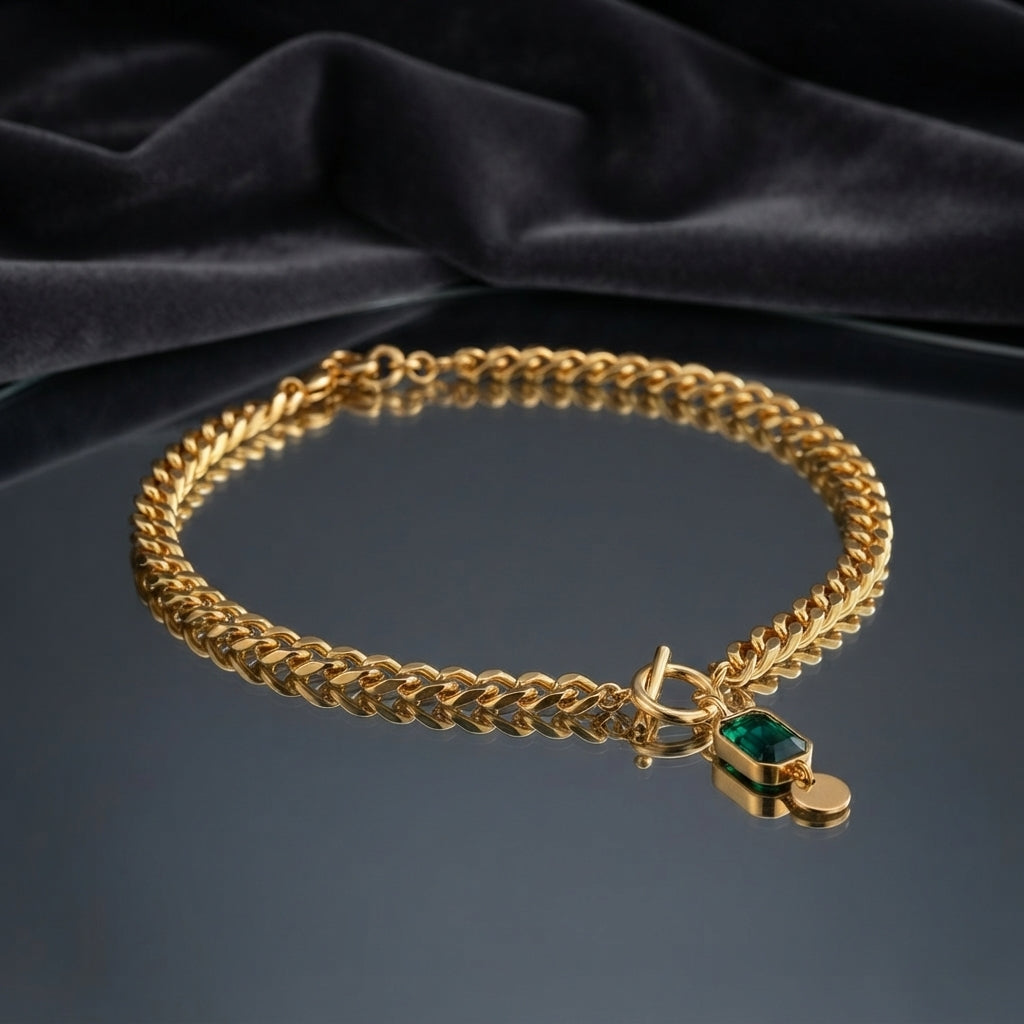 Gold Cuban Chain Emerald CZ Square Pendant Toggle Necklace on dark grey mirror surface with dark grey velvet drape backdrop