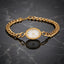 Gold Cuban Link Chain Oval Bracelet Watch in 18K gold-tone PVD stainless steel on dark grey marble surface showing bold Cuban curb link chain bracelet with smooth oval landscape gold-tone watch case and decorative white Roman numeral watch-face dial sticker with slim gold-tone hands and mirror reflection below