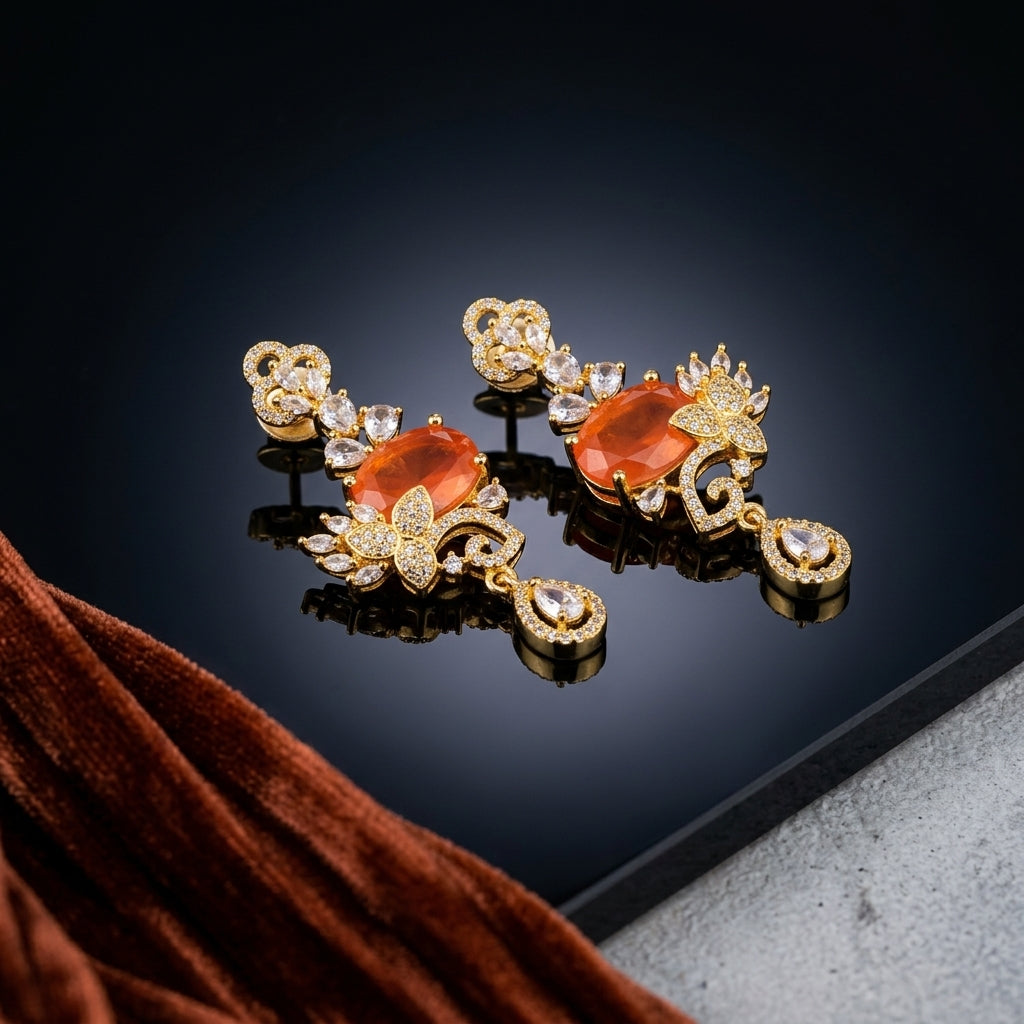 Gold-Tone Cushion Cut CZ Baroque Arabesque Filigree Butterfly Pavé & Pear Drop Chandelier Stud Earrings in Burnt Orange Carnelian on dark mirror surface with rust brown velvet fabric backdrop