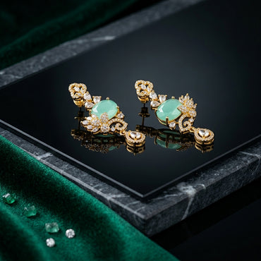 Gold-Tone Cushion Cut CZ Baroque Arabesque Filigree Butterfly Pavé & Pear Drop Chandelier Stud Earrings in Mint Jade Green on black mirror surface with green marble and emerald green velvet fabric backdrop