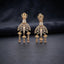 Gold CZ Champagne Baguette Crown and Chandelier Fan Jhumka Drop Earrings on dark charcoal slate surface with dark fabric backdrop showing 22K warm gold-tone grand chandelier jhumka pair with lotus crown baguette column fan chandelier body tiered jhumka bells and morganite pear drops