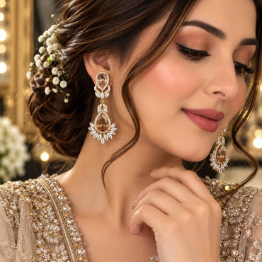 Gold CZ Double Teardrop Marquise Fan Chandelier Earrings in Champagne worn by South Asian bridal model with updo and baby's breath hair flowers on gold embroidered bridal outfit showing small pear CZ stud with infinity connector and large pear CZ drop with marquise CZ fan crown in warm bridal editorial setting