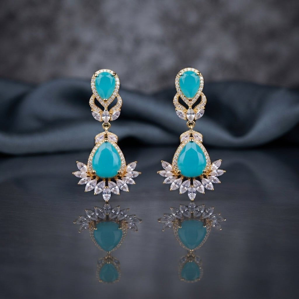 Gold CZ Double Teardrop Marquise Fan Chandelier Earrings in Turquoise pair on dark mirror surface with grey silk backdrop showing 18K gold-tone small turquoise pear CZ stud with white CZ pave halo infinity connector and large turquoise pear CZ drop with white CZ pave halo and marquise CZ fan crown with mirror reflection below