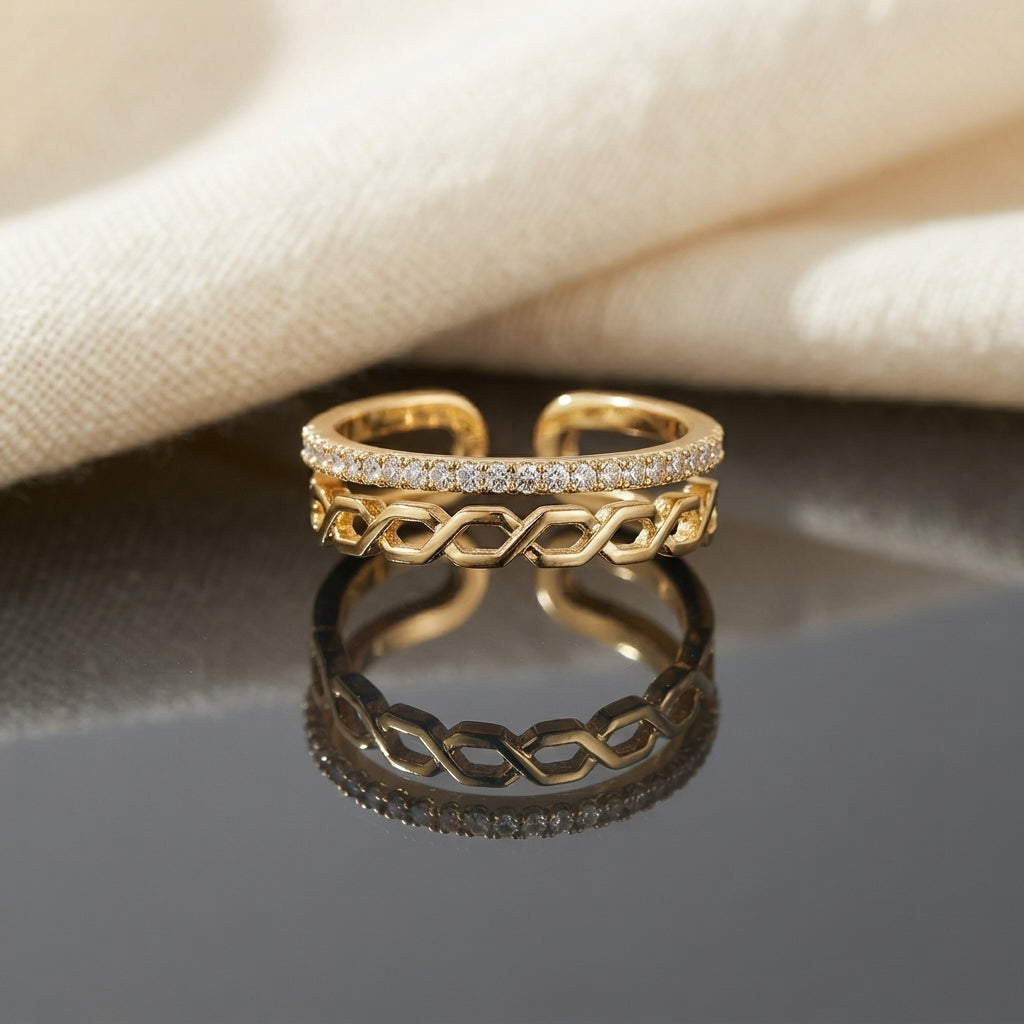 Gold CZ Eternity and Hexagon Chain Link Open Double Band Adjustable Ring on dark grey slate mirror surface with warm cream linen fabric backdrop showing 18K gold-tone open adjustable ring standing upright with slim micro-pave white CZ eternity upper band and open elongated hexagon chain link lower band in bright polished gold with sharp mirror reflection below