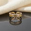 Gold CZ Eternity and Hexagon Chain Link Open Double Band Adjustable Ring on dark grey slate mirror surface with warm cream linen fabric backdrop showing 18K gold-tone open adjustable ring standing upright with slim micro-pave white CZ eternity upper band and open elongated hexagon chain link lower band in bright polished gold with sharp mirror reflection below