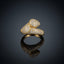 Gold CZ Micro-Pavé Double Dome Bypass Knot Sculptural Cocktail Ring — 22K gold-tone fully iced bypass knot cocktail ring with large round dome ball and cushion dome bar interlocking in sculptural knot, completely covered in dense round white CZ micro-pavé, on dark grey mirror surface with luxury editorial backdrop