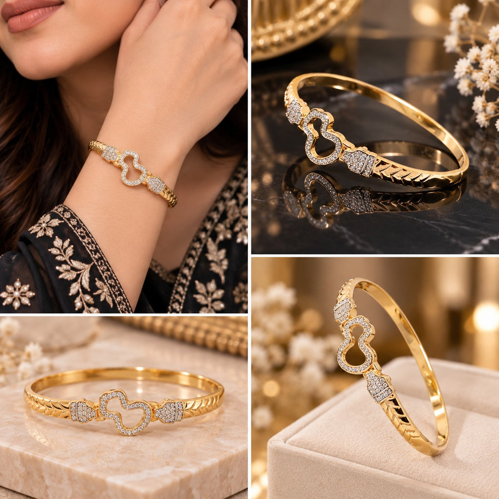 Gold CZ Pave Open Double Heart Bangle Bracelet worn on wrist in bridal editorial close-up showing 18K gold-tone rigid bangle with chevron engraved band open double-heart centre motif fully outlined in white CZ pave flanked by two pave CZ rectangular accent blocks on cream bridal embroidered outfit