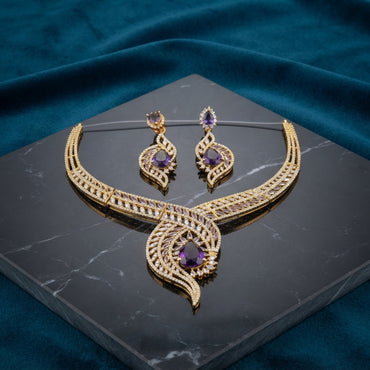 Gold CZ Peacock Feather Leaf Torque Necklace & Drop Earrings Set in Purple Amethyst CZ on dark grey marble with teal velvet backdrop