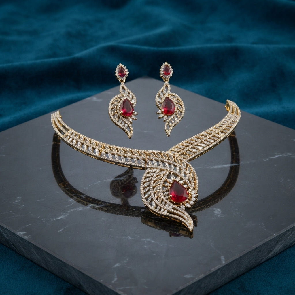 Gold CZ Peacock Feather Leaf Torque Necklace & Drop Earrings Set in Ruby Red CZ on dark grey marble with teal velvet backdrop