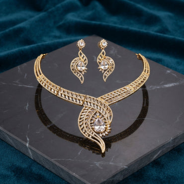 Gold CZ Peacock Feather Leaf Torque Necklace & Drop Earrings Set in White Crystal CZ on dark grey marble with teal velvet backdrop