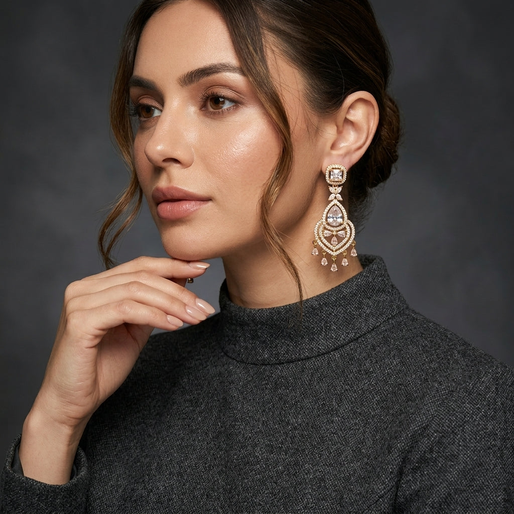 Gold CZ Princess Halo and Pear Chandelier Drop Earrings — 18-22K gold-tone bridal chandelier earrings with princess-cut white CZ square halo stud marquise butterfly connector large open Mughal arch teardrop frame in white CZ micro-pavé with pear CZ center and 5-drop pear CZ fringe displayed on dark black mirror surface with charcoal satin backdrop