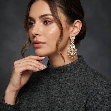 Gold CZ Princess Halo and Pear Chandelier Drop Earrings — 18-22K gold-tone bridal chandelier earrings with princess-cut white CZ square halo stud marquise butterfly connector large open Mughal arch teardrop frame in white CZ micro-pavé with pear CZ center and 5-drop pear CZ fringe displayed on dark black mirror surface with charcoal satin backdrop
