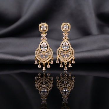 Gold CZ Princess Halo and Pear Chandelier Drop Earrings — 18-22K gold-tone bridal chandelier earrings with princess-cut white CZ square halo stud marquise butterfly connector large open Mughal arch teardrop frame in white CZ micro-pavé with pear CZ center and 5-drop pear CZ fringe displayed on dark black mirror surface with charcoal satin backdrop