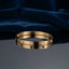 Gold CZ Studded Screw Motif Hinged Bangle Bracelet worn on right wrist of female model in navy blue blazer and white top with hands clasped on dark wood table showing 18K warm yellow gold-tone hinged bangle with alternating screw motif bezels and flush bezel-set round white CZ stones in luxury boutique setting