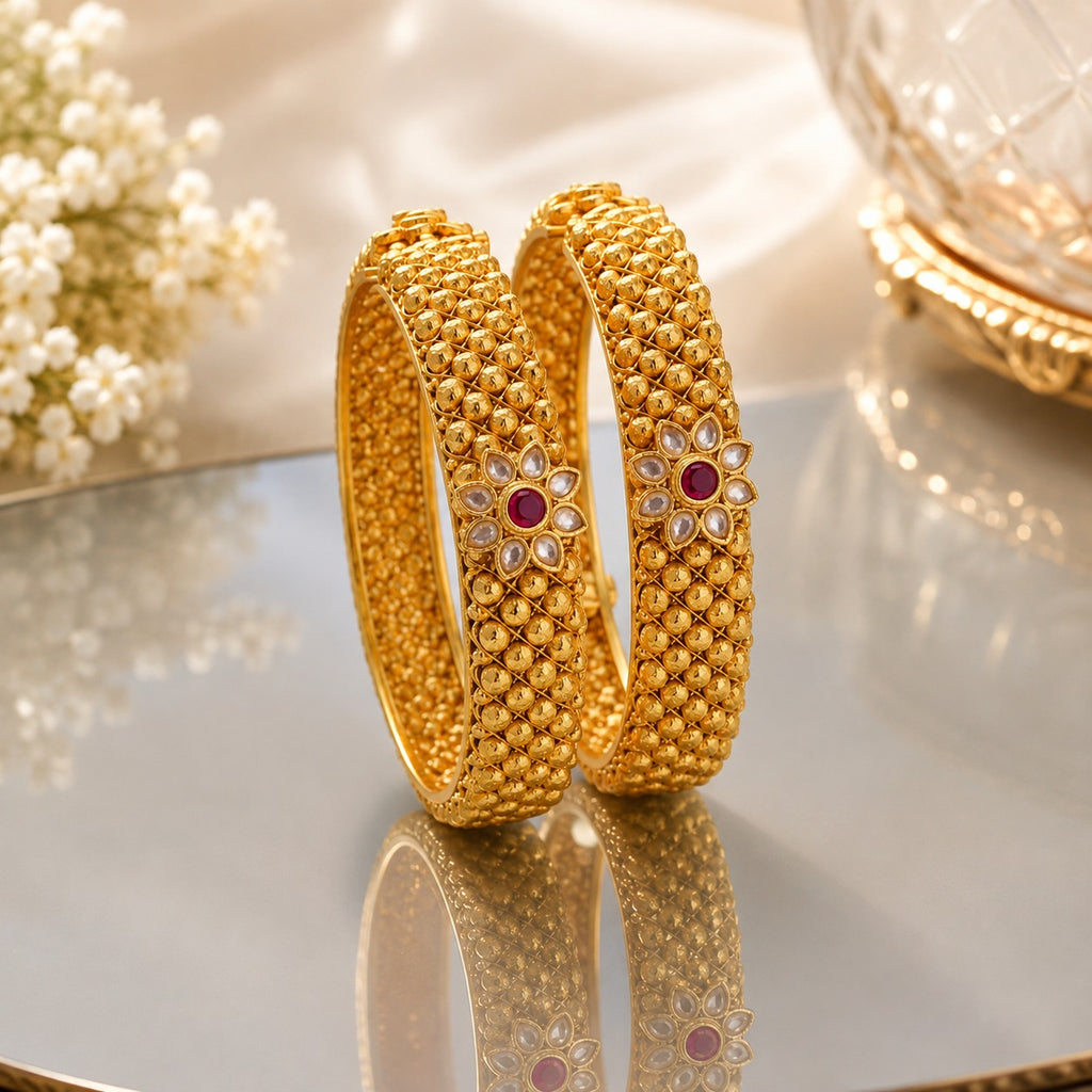 Gold-Tone Wide Dome Ball Granule & Kundan Polki Flower Ruby CZ Kada Bangle Set of 2 on mirrored tray with ivory silk fabric and baby's breath flowers backdrop