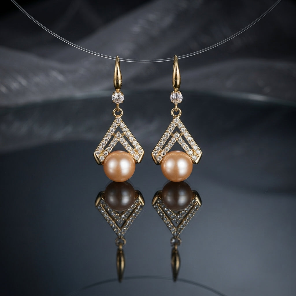 Gold-Tone Double Chevron CZ Micro-Pavé Crown & Peach Freshwater Pearl Drop Lever-Back Earrings suspended on clear wire on dark grey mirror surface with dark silk fabric backdrop