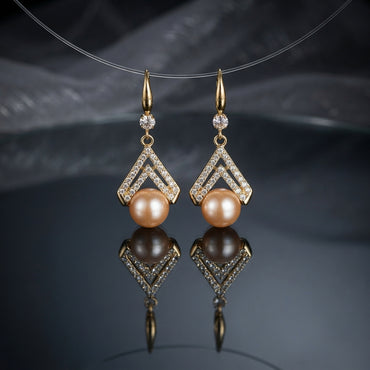 Gold-Tone Double Chevron CZ Micro-Pavé Crown & Peach Freshwater Pearl Drop Lever-Back Earrings suspended on clear wire on dark grey mirror surface with dark silk fabric backdrop
