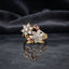 Gold Double Flower Cluster CZ Cocktail Ring in blush pink morganite CZ accent variant — luxury flat-lay on mirror surface with charcoal silk backdrop