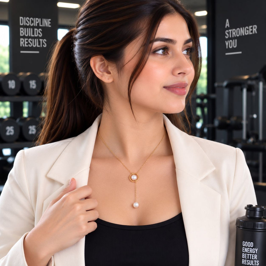 Gold Double Pearl Circle Lariat Y-Necklace worn by model in white blazer and black top at gym setting with dumbbell rack backdrop