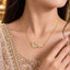 Gold Dual Leaf CZ Pavé & Marquise Pendant Collarbone Necklace worn by bridal model in gold embroidered lehenga with gold bokeh backdrop