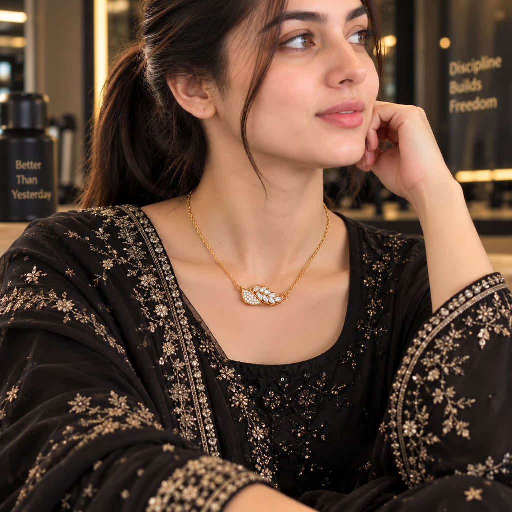 Gold Dual Leaf CZ Pavé & Marquise Pendant Collarbone Necklace worn by model in black embroidered outfit at gym setting
