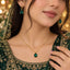 Gold Emerald Pear CZ Solitaire Pendant Necklace & Hoop Drop Earrings Set worn by bridal model in deep forest green embroidered lehenga with gold bokeh backdrop