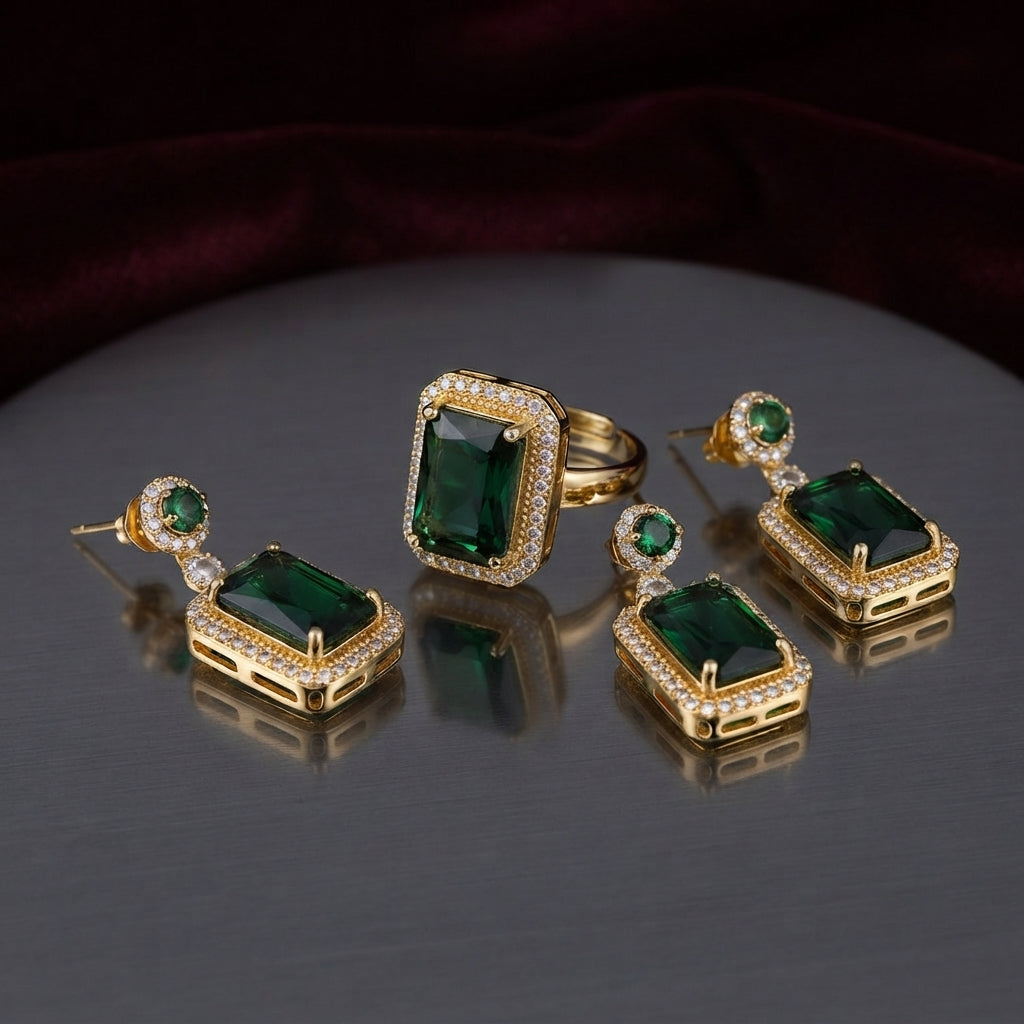 Gold Emerald Rectangle CZ Double Halo Drop Earrings and Cocktail Ring close-up — showing large emerald green rectangle CZ in double white CZ pavé halo with small round emerald CZ top accent on 22K gold, luxury flat-lay on round mirror tray with burgundy velvet backdrop