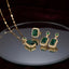 Gold Emerald Rectangle CZ Double Halo Jewelry Set — 3-piece matching set of pendant necklace, drop earrings and cocktail ring each with large deep vivid emerald green rectangle CZ in double round white CZ micro-pavé halo on 22K gold, luxury flat-lay on round mirror tray with burgundy velvet backdrop
