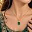 Gold Emerald Rectangle CZ Halo Pendant Necklace close-up worn by bridal model in deep green gold-embroidered lehenga with gold bokeh backdrop