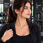 Gold Engraved Circle Dog Tag Pendant Necklace worn by model in black gym jacket at gym setting with dumbbell rack backdrop