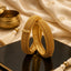 Gold-Tone Filigree Braided Kada Bangle Set of 2 on black mirror surface with cream silk fabric and gold pot backdrop