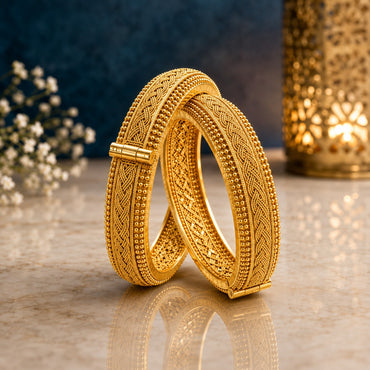Gold-Tone Filigree Braided Kada Bangle Set of 2 on marble surface with blue backdrop and white baby's breath flowers