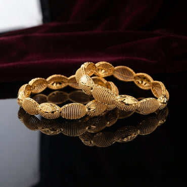 Gold Filigree Mesh Starburst Oval Bead Kangan Bangle Set Pair of 2 flat lay on dark black mirror surface with deep burgundy wine velvet backdrop showing two 22K antique gold-tone rigid slip-on kangan bangles with continuous oval barrel bead links featuring alternating filigree mesh net texture and diamond-cut starburst fan engraved panels with small gold ball connectors and mirror reflection below