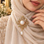 Gold Filigree Pearl Hijab Brooch Pin in antique 22K gold-tone worn on cream shimmer hijab in bridal editorial close-up showing ornate diamond-shaped arabesque filigree brooch with large round mabe pearl centre in rope-twist bezel four fan petal accents intricate scrollwork and baroque teardrop pearl drop pendant on gold embroidered bridal outfit backdrop