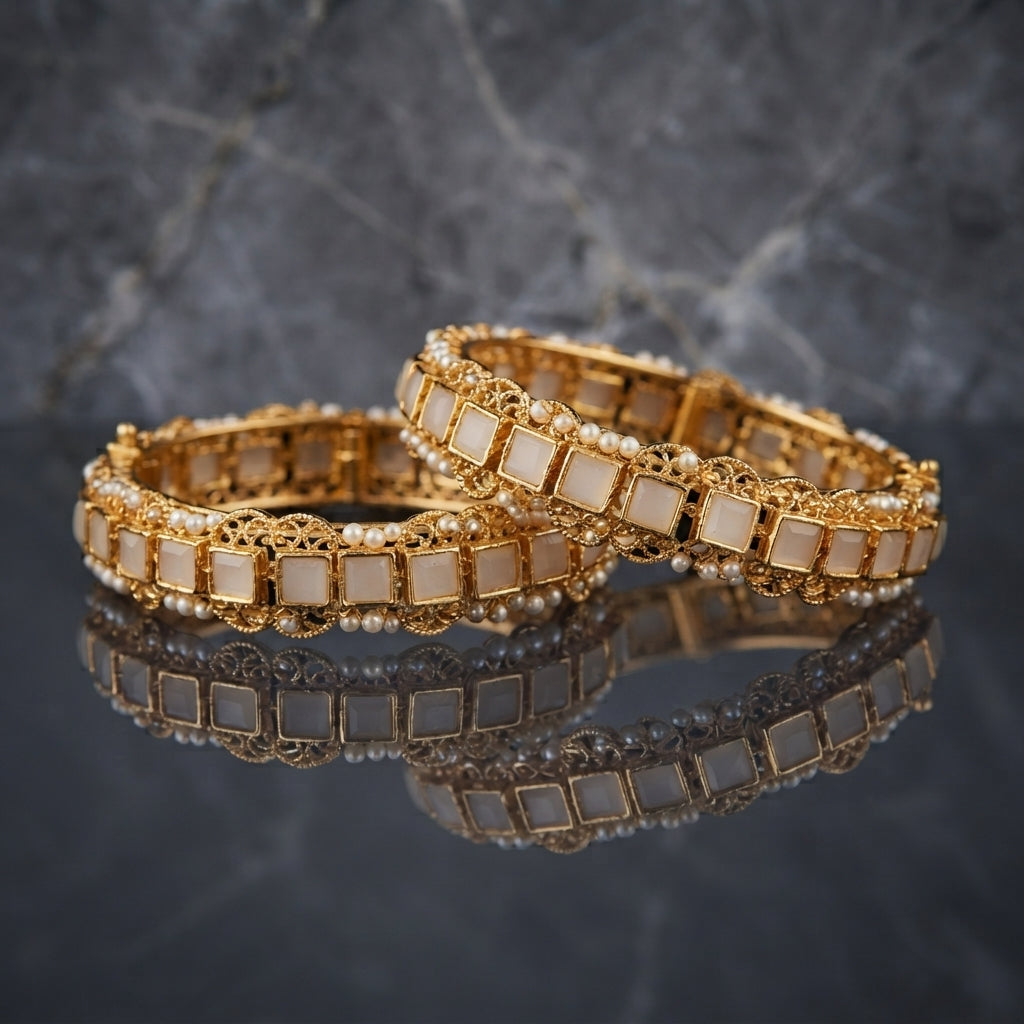 Gold Filigree Square Stone Seed Pearl Bangles Bridal Pair in 18K antique gold-tone plating on dark grey mirror surface with marble backdrop showing two rigid bangles with alternating square white ivory stone tiles in gold box-bezel settings and ornate gold filigree scroll medallions with seed pearl bead top and bottom edges and mirror reflection below