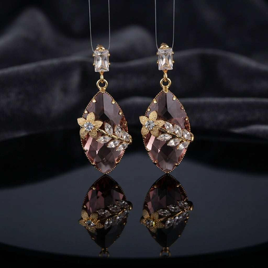 Gold Floral CZ Leaf Crystal Gem Drop Earrings in Ruby Red showing pair suspended on monofilament wire against dark backdrop with baguette CZ stud top large faceted diamond-shape ruby red crystal drop with gold daisy flower and marquise CZ leaf sprig overlay and mirror reflection below