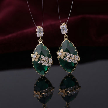 Gold Floral CZ Leaf Crystal Gem Drop Earrings in Crystal Clear showing pair suspended on monofilament wire against dark silk backdrop with baguette CZ stud top large faceted diamond-shape crystal clear drop with gold daisy flower and marquise CZ leaf sprig overlay and mirror reflection below