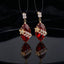 Gold Floral CZ Leaf Crystal Gem Drop Earrings in Smoky Mauve showing pair suspended on monofilament wire against dark silk backdrop with baguette CZ stud top large faceted diamond-shape smoky mauve crystal drop with gold daisy flower and marquise CZ leaf sprig overlay and mirror reflection below