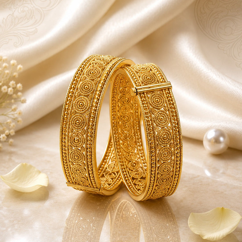 Gold-Tone Wide Granule Concentric Circle Spiral Kada Bangle Set of 2 on cream reflective surface with white silk fabric, pearl and rose petals backdrop