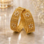 Gold-Tone Wide Granule Kundan Polki Five-Petal Flower Panel Kada Bangle Set of 2 leaning on gold marble surface with crystal candle holder and baby's breath flowers backdrop