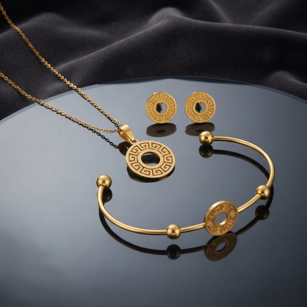 Gold Greek Key Open-Work Donut Disc Pendant Necklace Cuff Bangle Earrings Set — 3-piece all-gold set of fine cable chain with Greek key open-work donut pendant, open ball-end cuff bangle with center Greek key disc, and matching Greek key donut stud earrings, luxury flat-lay on round mirror tray with dark charcoal silk backdrop