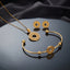 Gold Greek Key Open-Work Donut Disc Pendant Necklace Cuff Bangle Earrings Set — 3-piece all-gold set of fine cable chain with Greek key open-work donut pendant, open ball-end cuff bangle with center Greek key disc, and matching Greek key donut stud earrings, luxury flat-lay on round mirror tray with dark charcoal silk backdrop